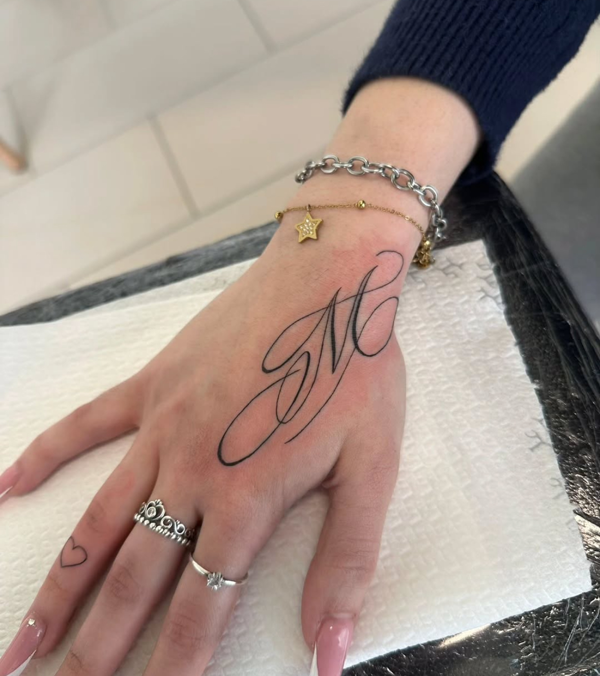 Tatuaggio lettering corsivo 'M' sulla mano